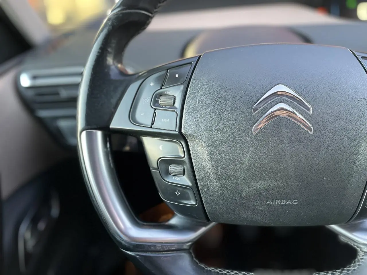 Gros plan sur le volant noir de la Citroën C4 Picasso 2014, avec commandes intégrées et logo chromé au centre.