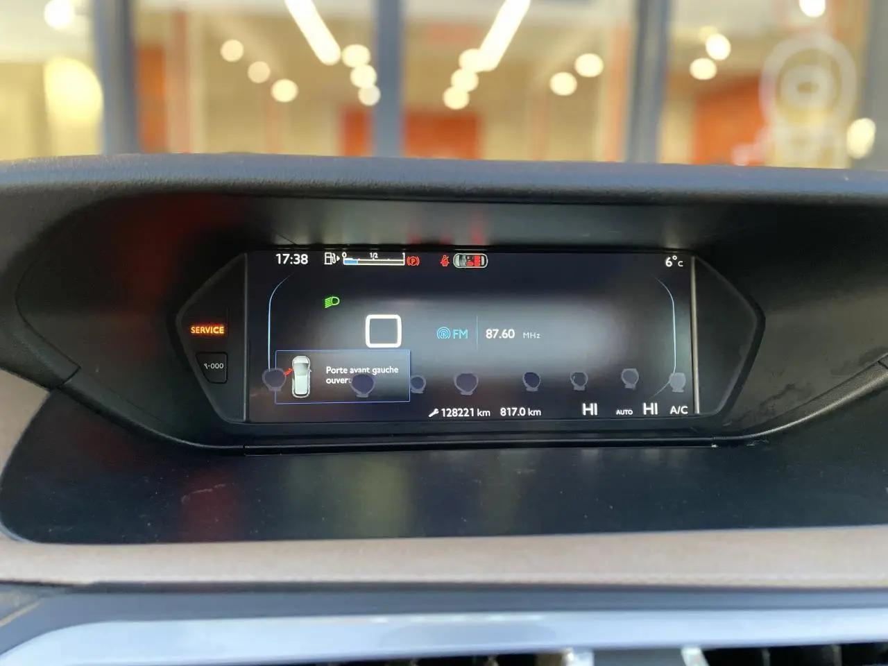 Tableau de bord numérique de Citroën C4 Picasso 2014 affichant la radio FM et l'alerte porte avant gauche ouverte.