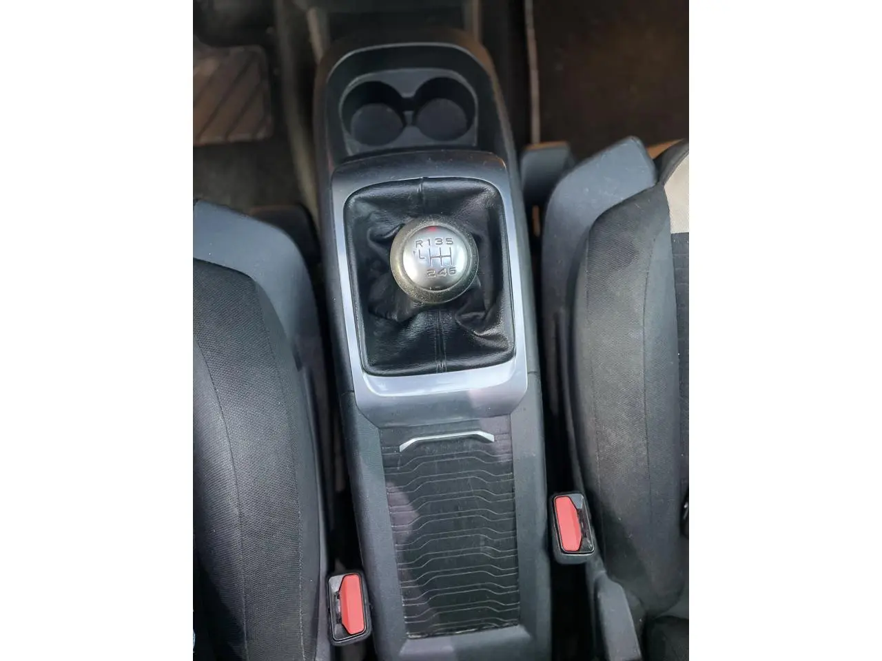Le levier de vitesse manuel de la Citroën C4 Picasso 2014 vu de dessus entre les sièges noirs.