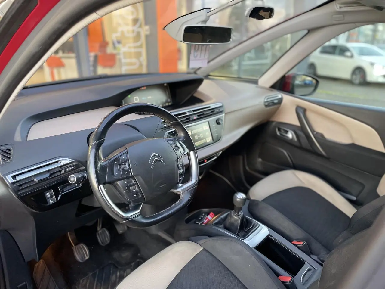 Intérieur de la Citroën C4 Picasso 2014 vu côté conducteur, volant multifonction et sellerie bicolore noire et beige.