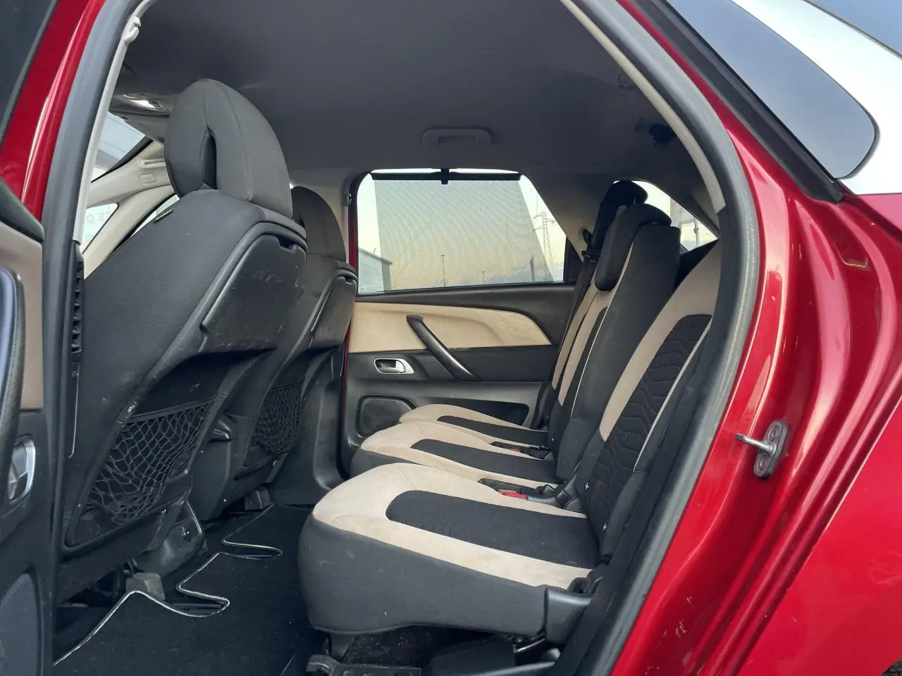 Vue latérale intérieure sur les sièges arrière bicolores d'une Citroën C4 Picasso rouge foncé de 2014.