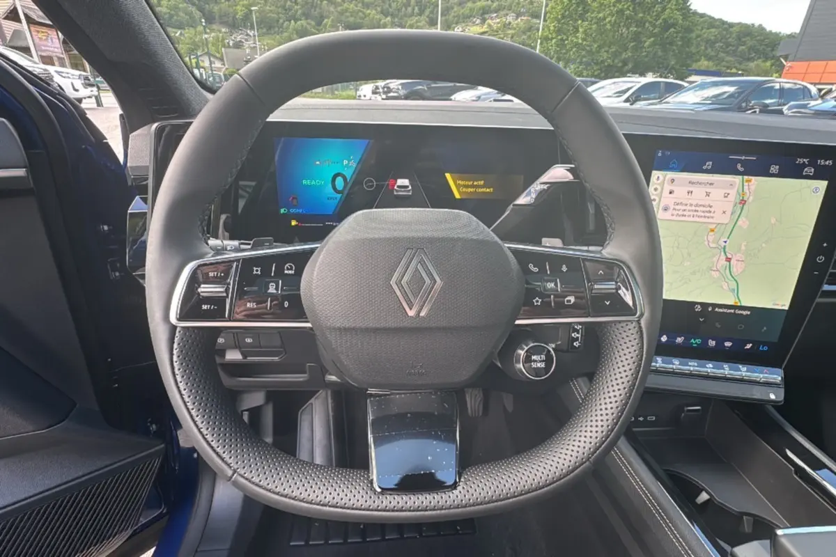 Vue intérieure centrée sur le volant perforé du Renault Austral E-Tech 200, avec tableau de bord numérique et écran tactile.