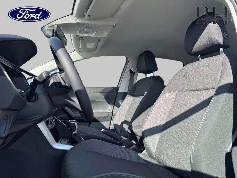 Vue intérieure côté conducteur d'une Volkswagen Taigo 2024 avec sièges tissu noir et volant cuir multifonction