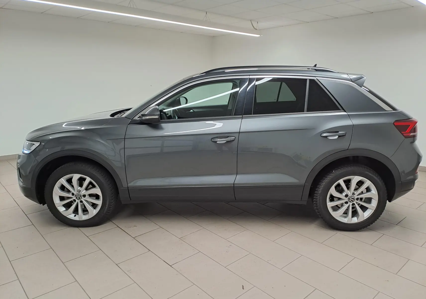 Profil côté gauche d'un Volkswagen T-Roc 2024 gris Indium avec jantes alliage 17'' Johannesburg en intérieur.