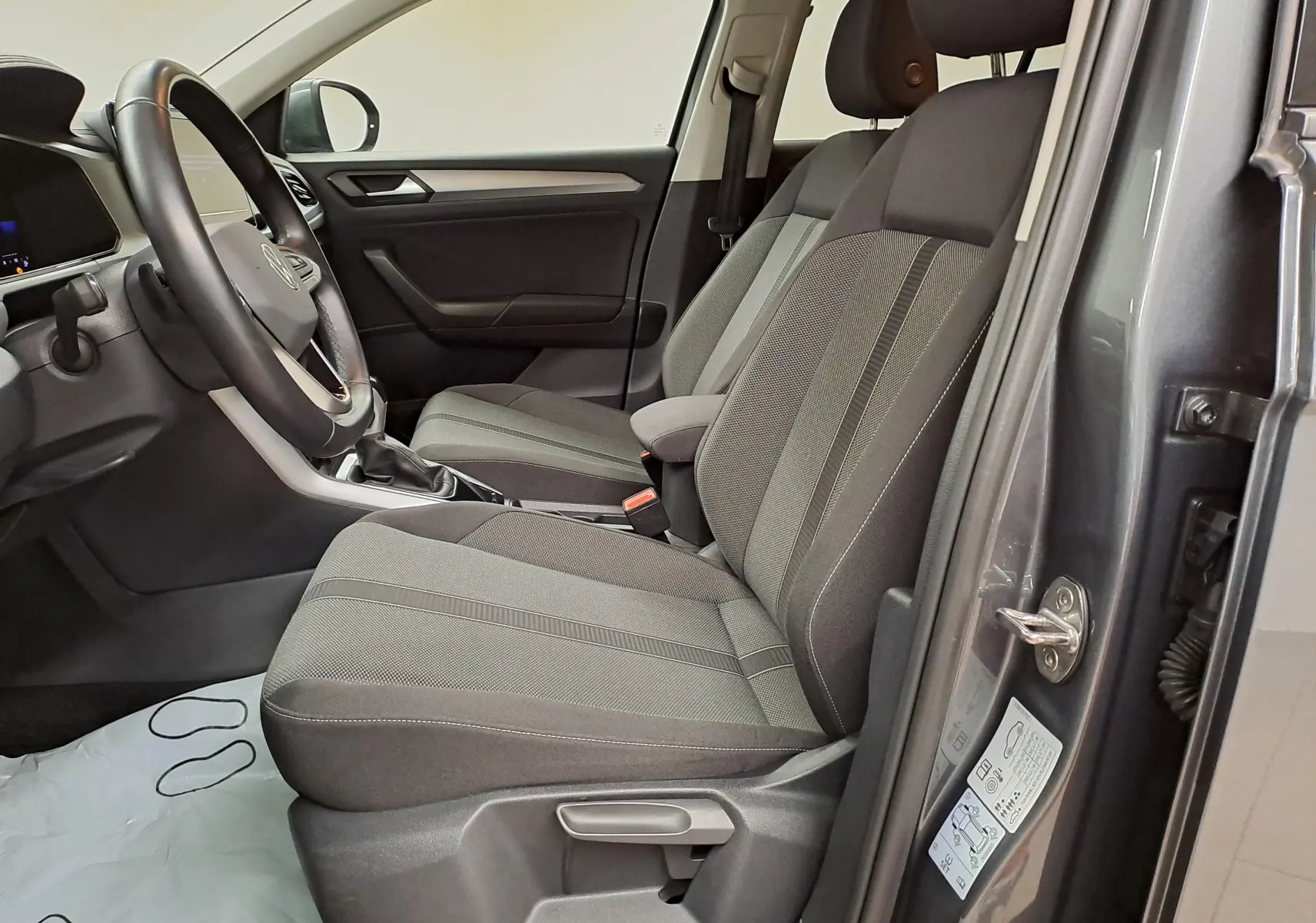 Intérieur avant droit du Volkswagen T-Roc 1.5 TSI 2024 en gris Indium, sièges tissu gris et tableau de bord sobre.