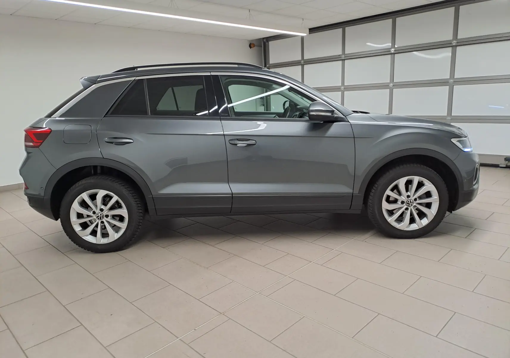 Profil côté gauche du Volkswagen T-Roc 1.5 TSI 150 gris Indium avec jantes alliage 17'' Johannesburg en intérieur.