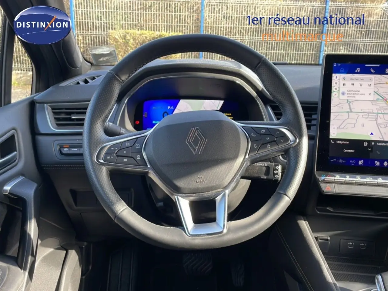 Vue intérieure centrée sur le volant noir du Renault Symbioz 2025, avec tableau de bord numérique et écran tactile latéral.