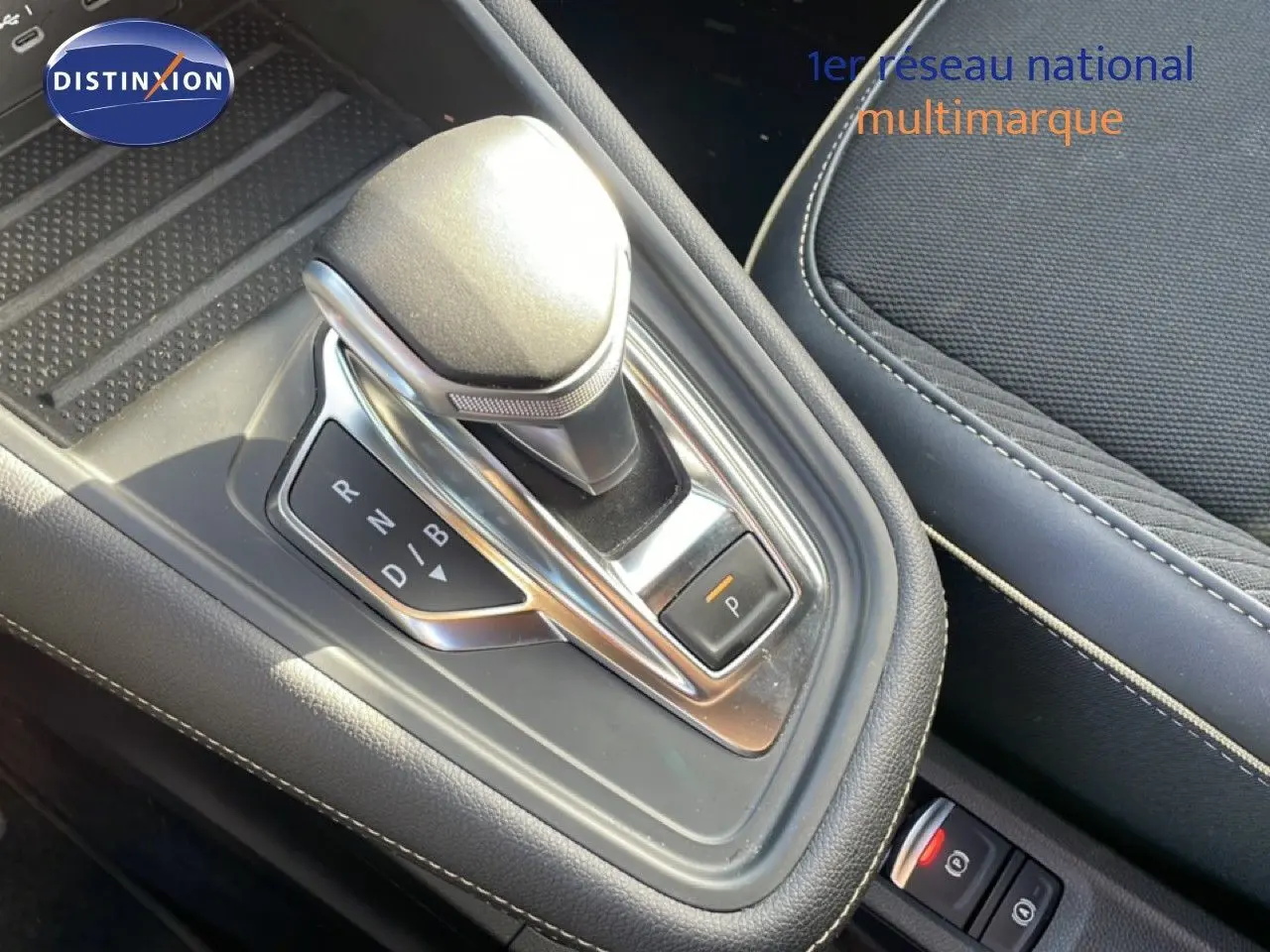 Gros plan sur la commande de boîte automatique et l'accoudoir en tissu gris du Renault Symbioz 2025.