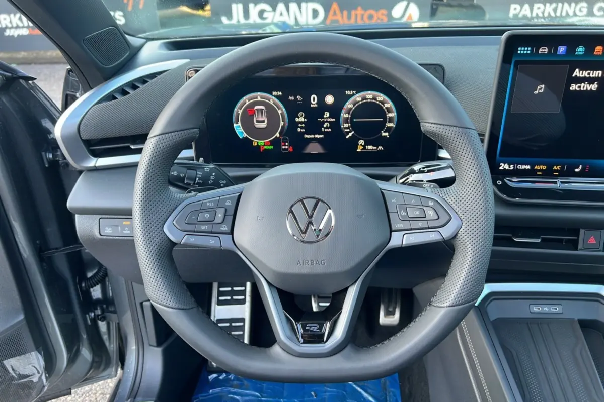 Vue centrée sur le volant cuir perforé Volkswagen T-Roc R-Line gris loup avec tableau de bord digital et écran tactile.