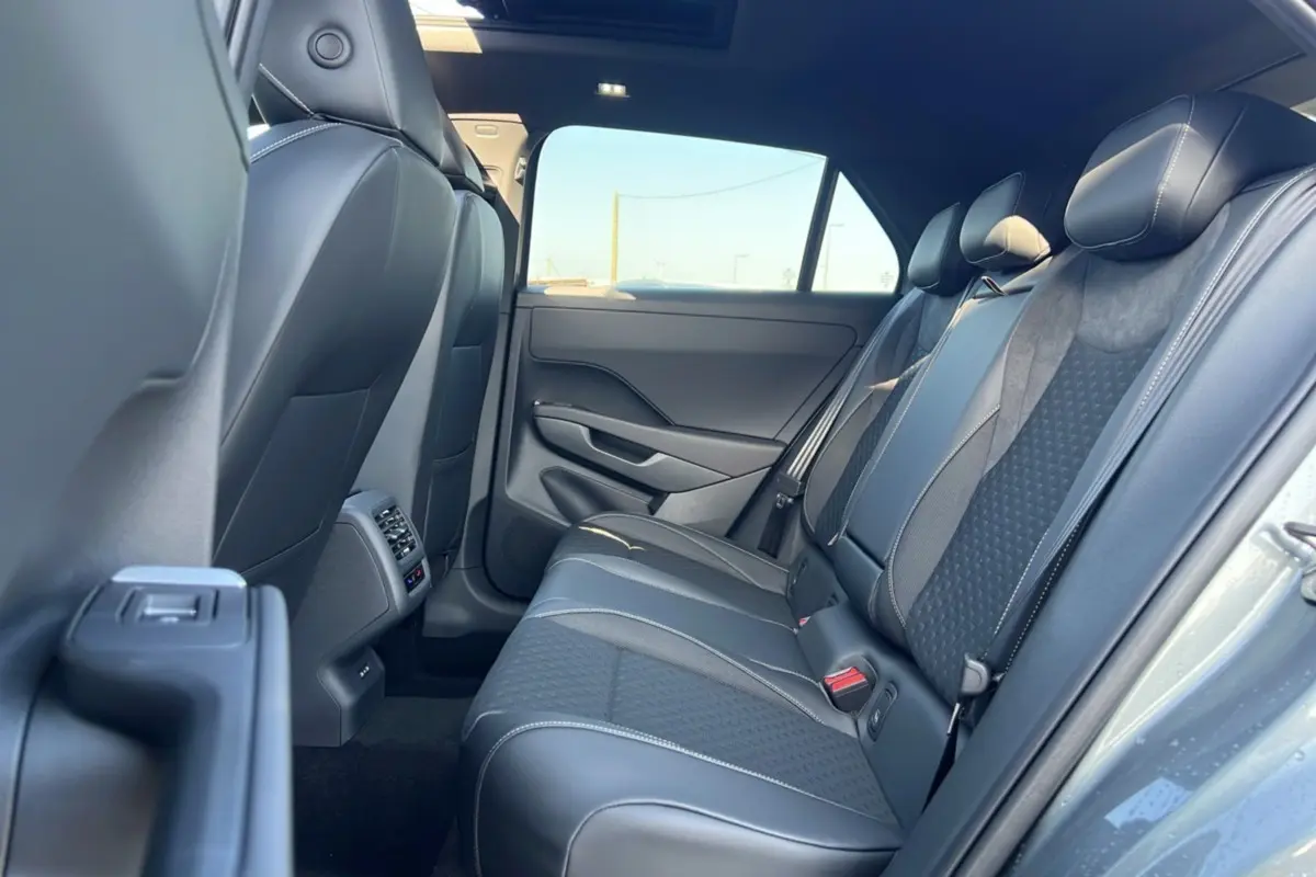 Vue intérieure arrière droite du Volkswagen T-Roc 2026 gris loup, montrant les sièges arrière en tissu et cuir avec surpiqûres blanches.