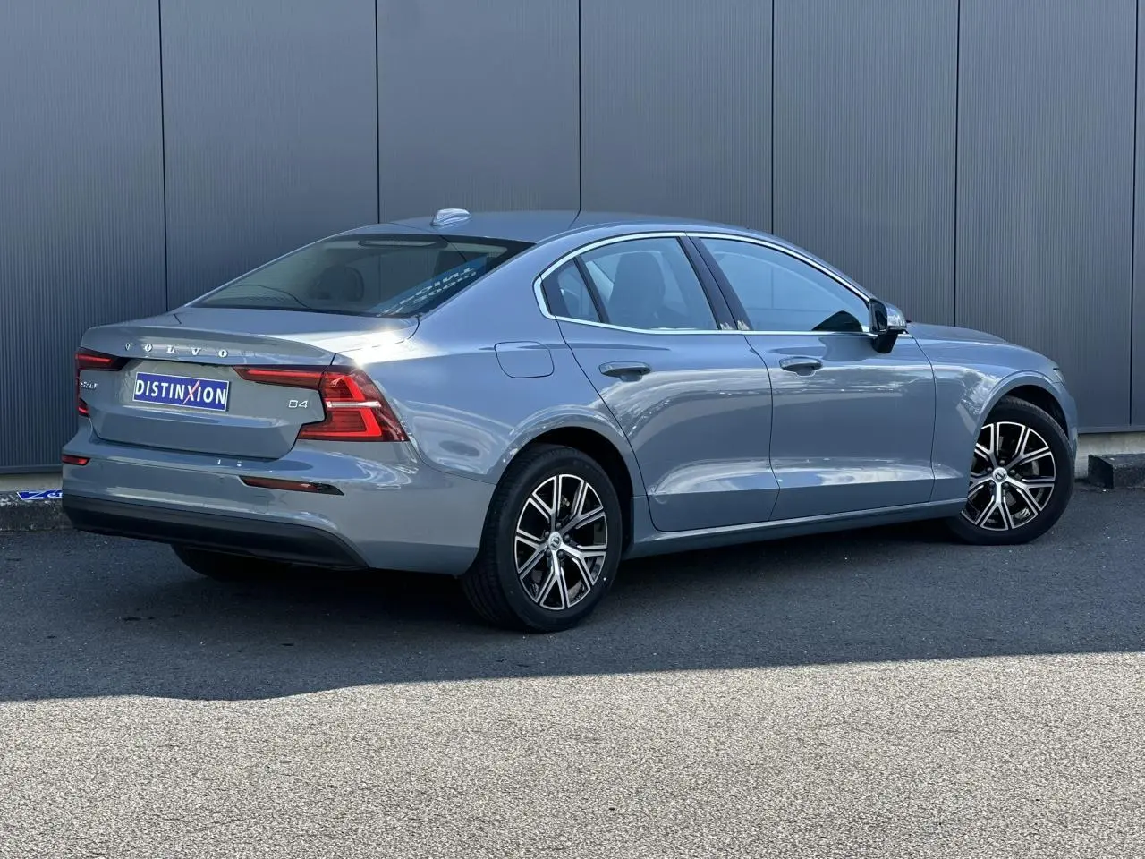 Volvo S60 B4 gris Thunder vue 3/4 arrière droit avec jantes alliage 17 pouces et contours de fenêtres chromés.