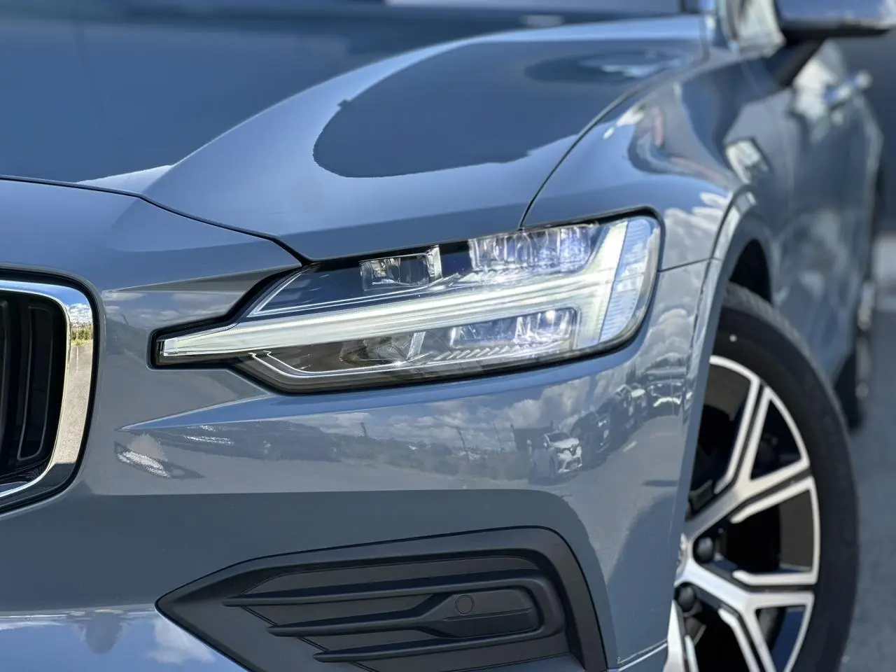 Gros plan sur l'avant droit d'une Volvo S60 gris Thunder, mettant en valeur son phare LED et jante alliage 17 pouces.