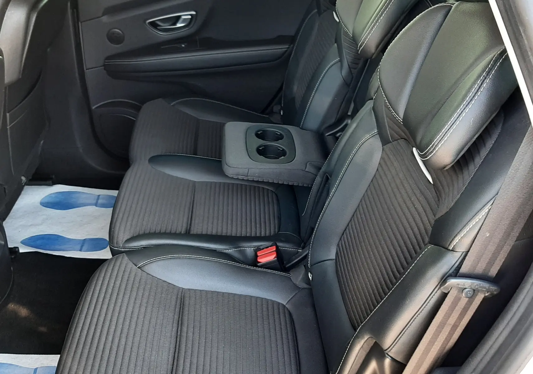 Vue latérale droite de l'intérieur arrière du Renault Scénic IV 2018, sièges noirs avec accoudoir central et porte ouverte.