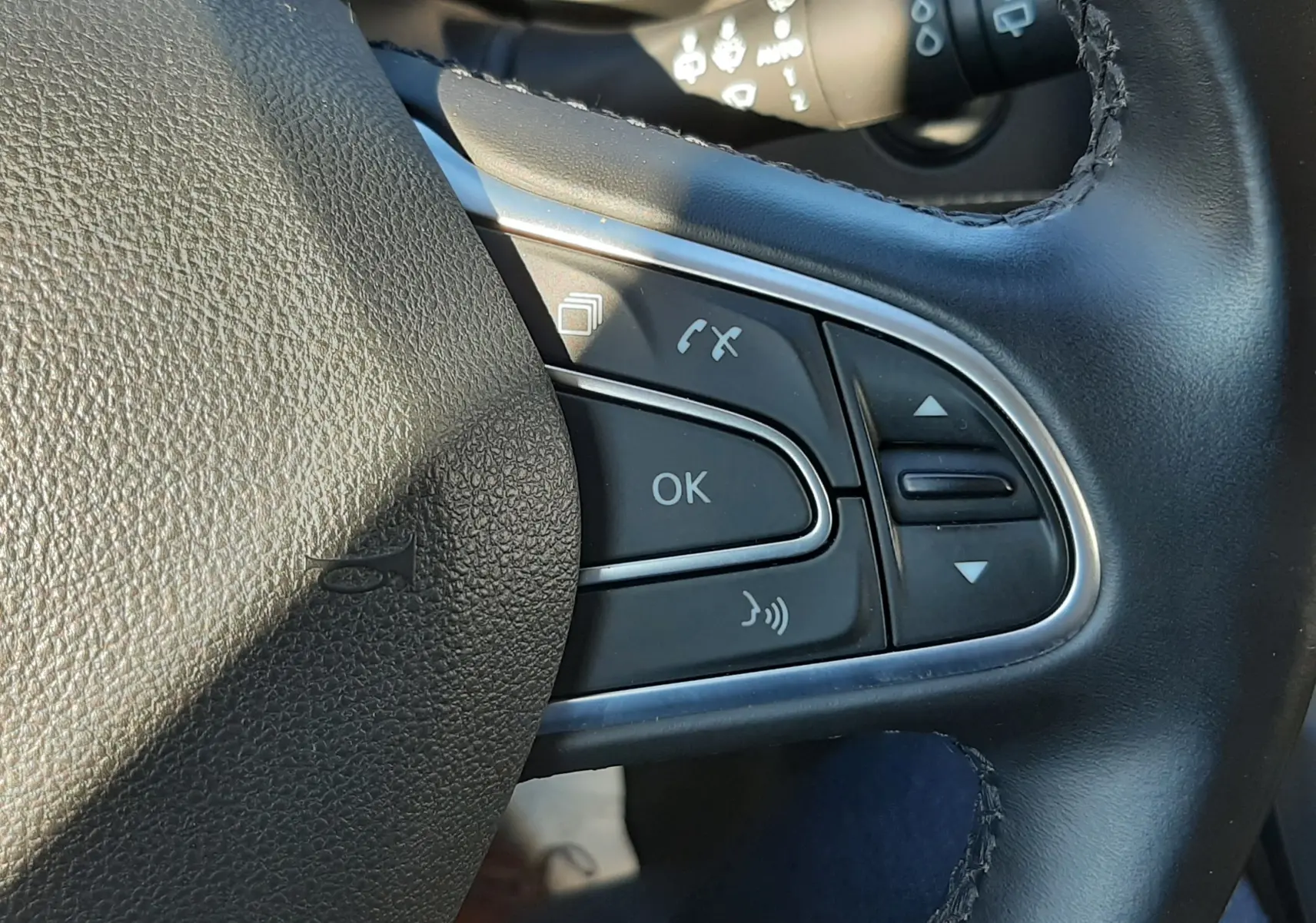 Gros plan sur les commandes multifonctions noires à droite du volant en cuir du Renault Scenic IV 2018.