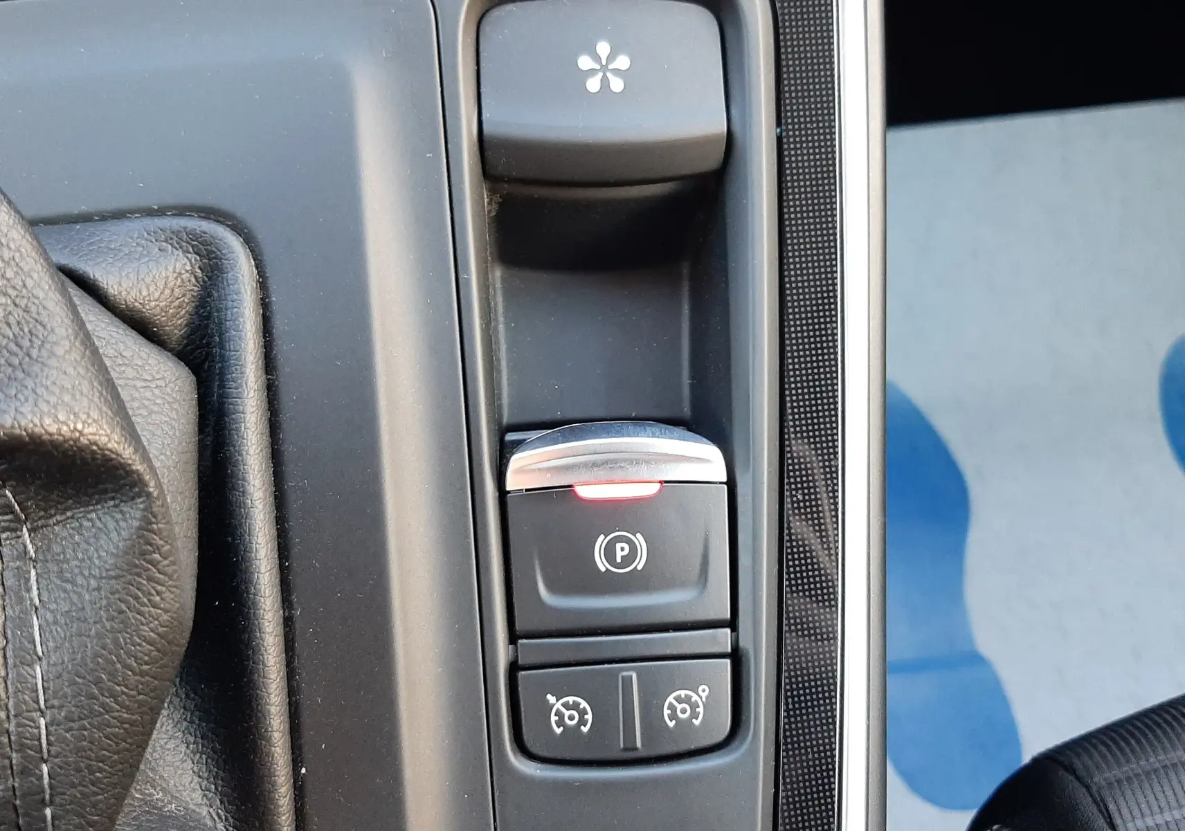 Gros plan sur les commandes de la console centrale du Renault Scenic IV, avec bouton de frein à main électronique et régulateur de vitesse.