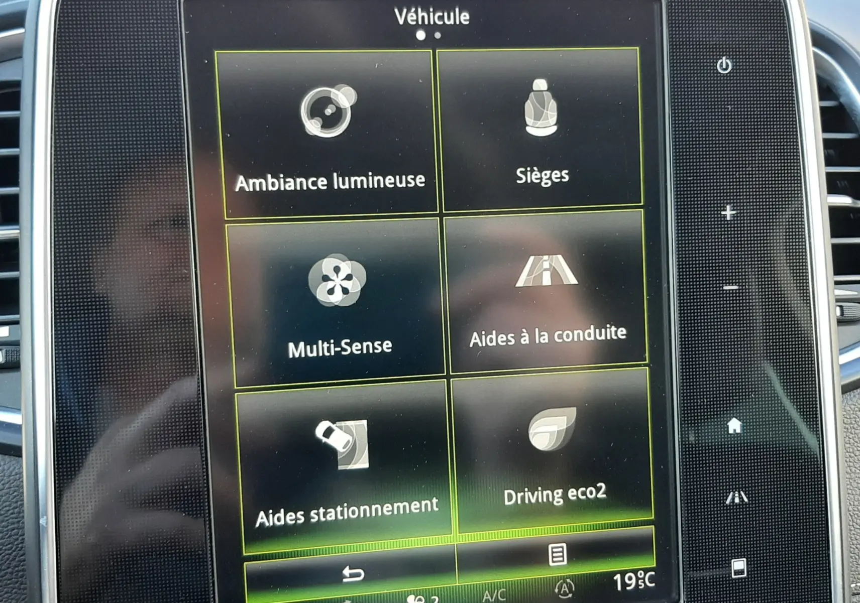 Écran tactile central du Renault Scenic IV 2018 montrant les options véhicule avec interface noire et boutons latéraux.