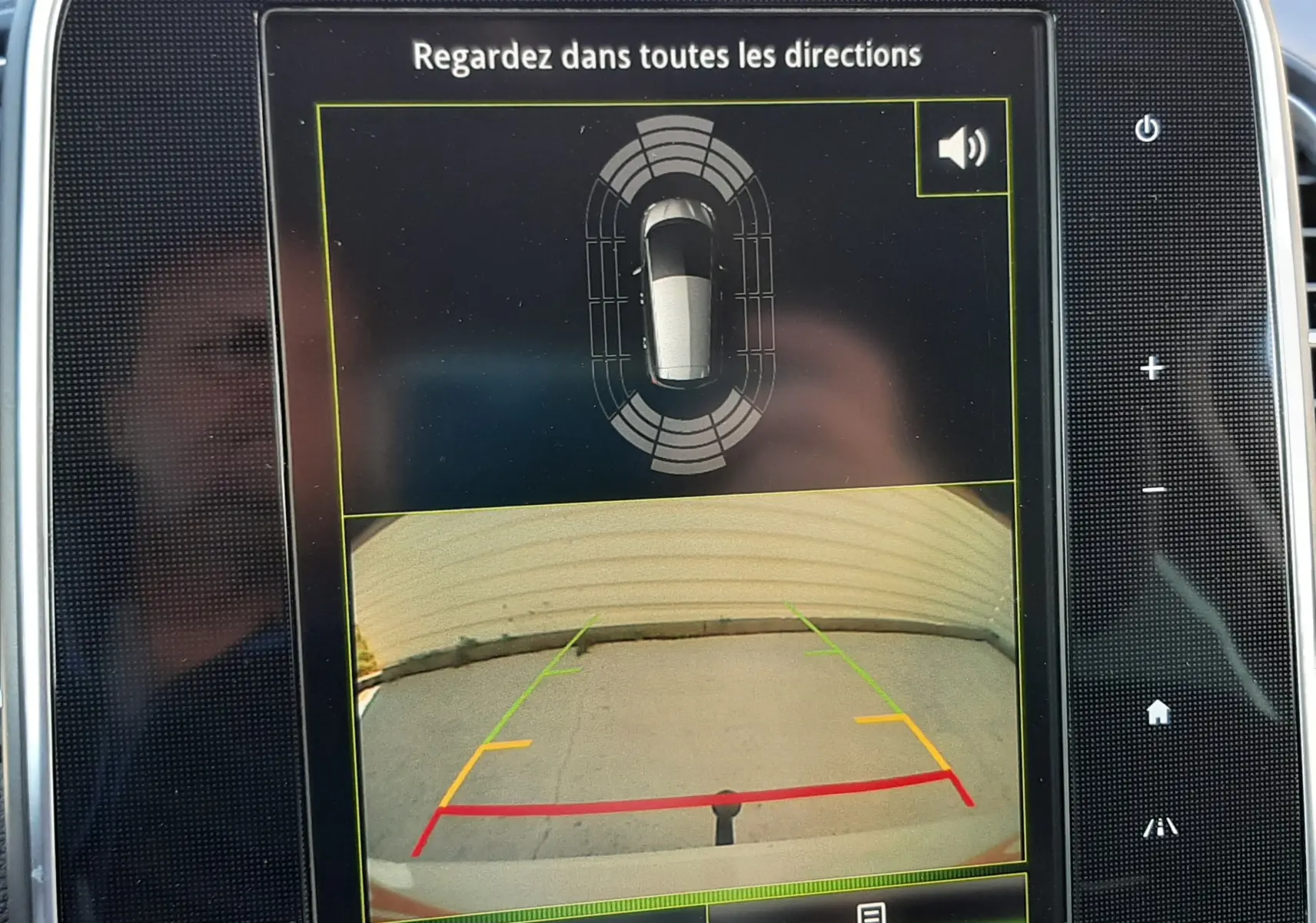 Écran central de Renault Scenic IV montrant la caméra de recul et l'alerte de proximité autour du véhicule.