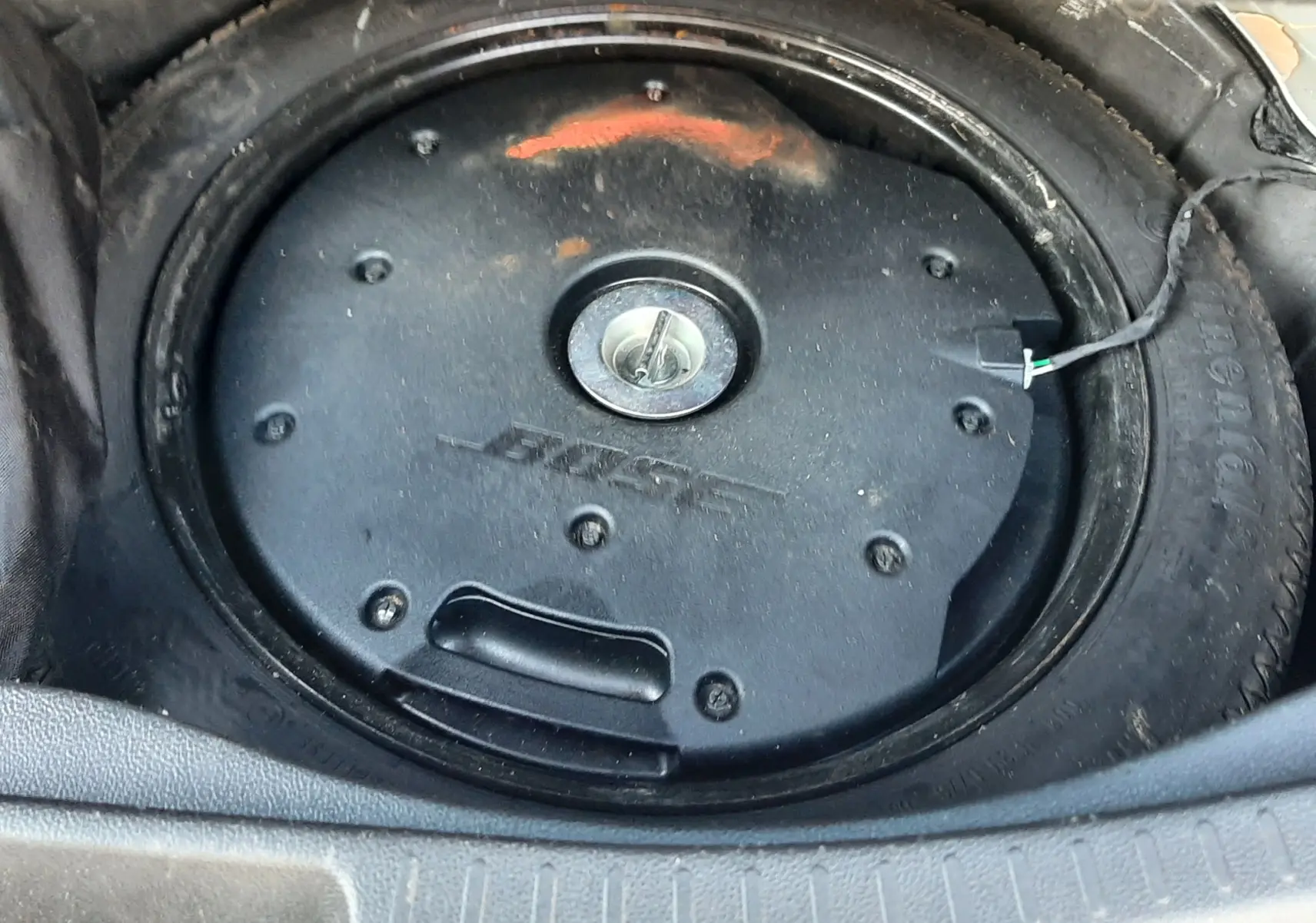 Gros plan sur le caisson de basse Bose intégré dans la roue de secours du coffre d'un Renault Scenic IV blanc nacré.