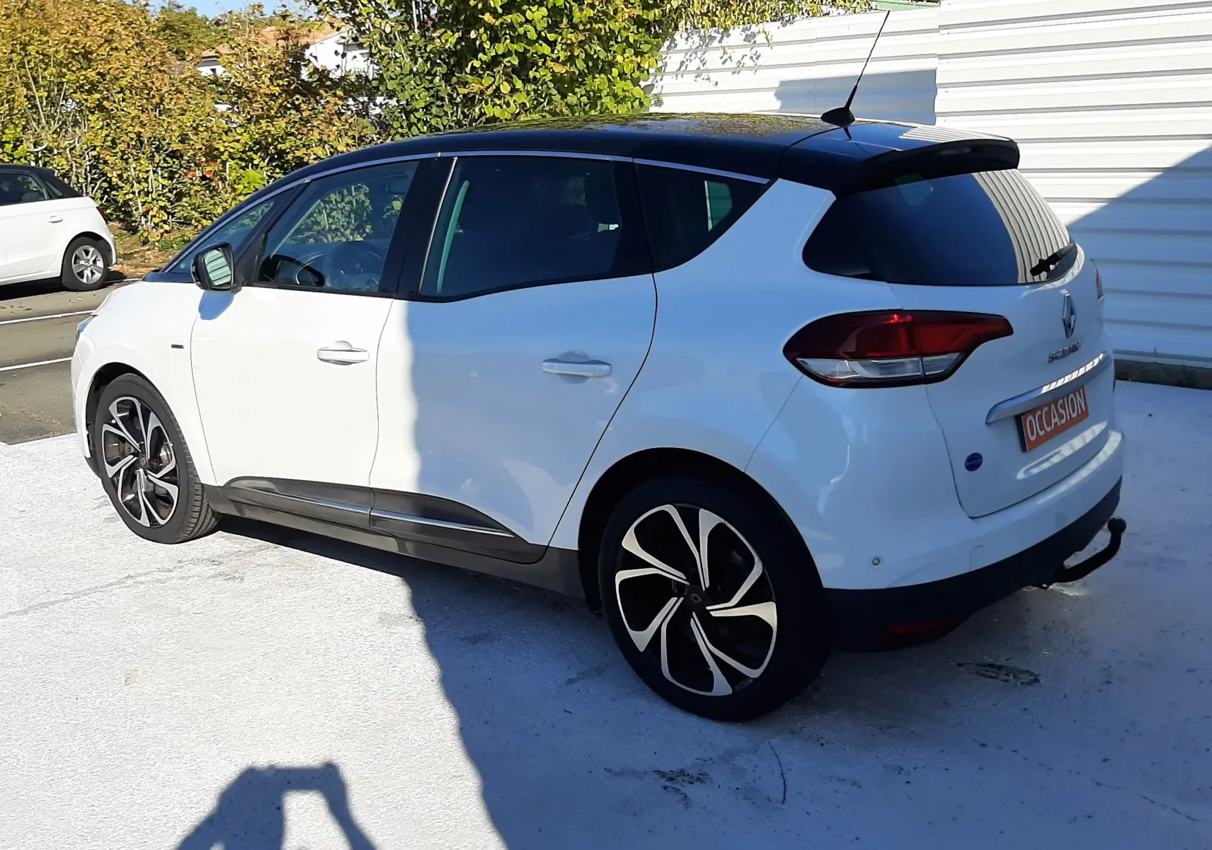Renault Scénic IV blanc nacré avec toit noir, vue 3/4 arrière côté gauche, jantes alliage distinctives.