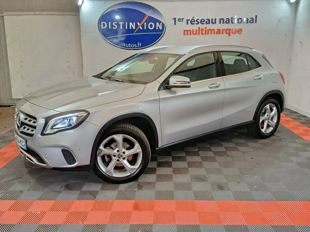 Mercedes GLA 200 d gris clair vue 3/4 avant droit, avec jantes alliage et feux LED allumés en intérieur showroom.