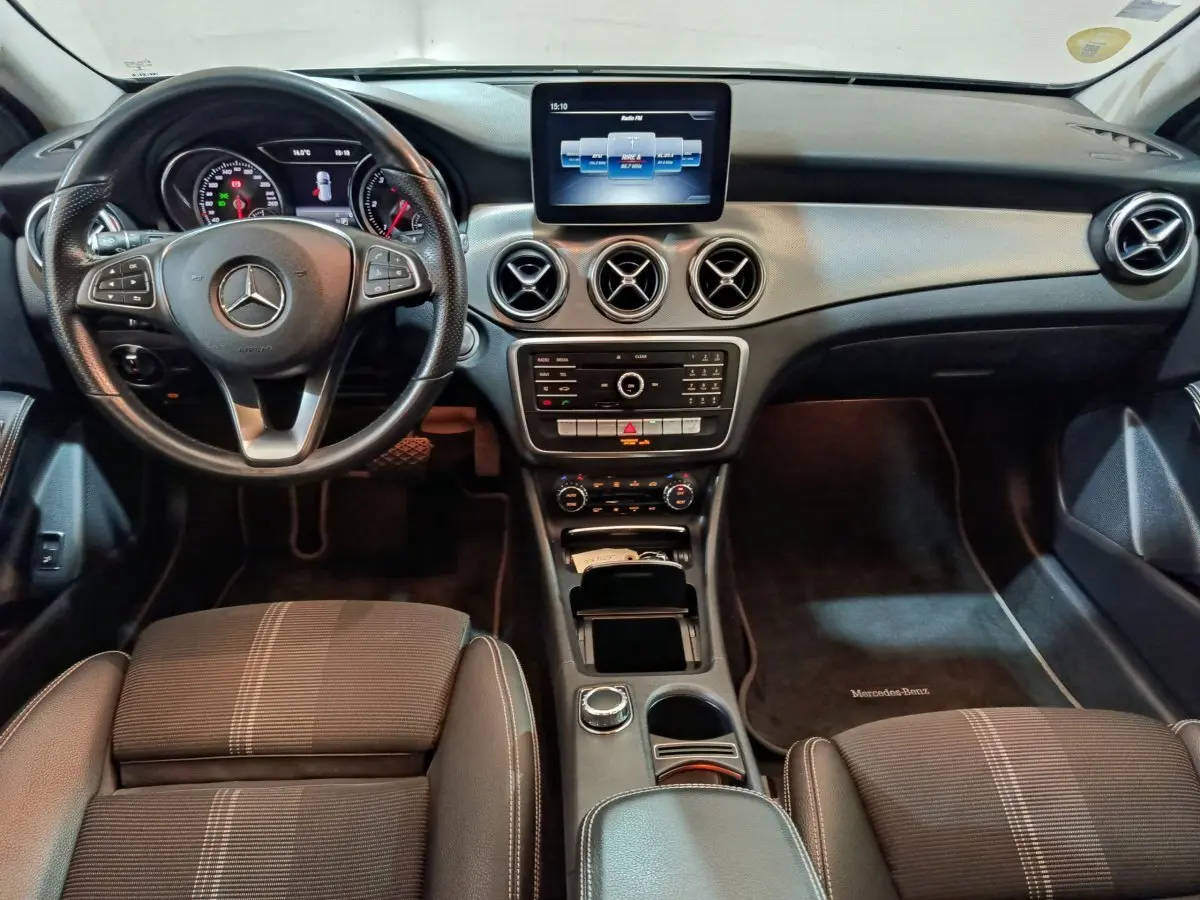 Vue intérieure avant du Mercedes GLA 200 d Business Executive 2018, tableau de bord noir avec écran central et volant cuir multifonctions.