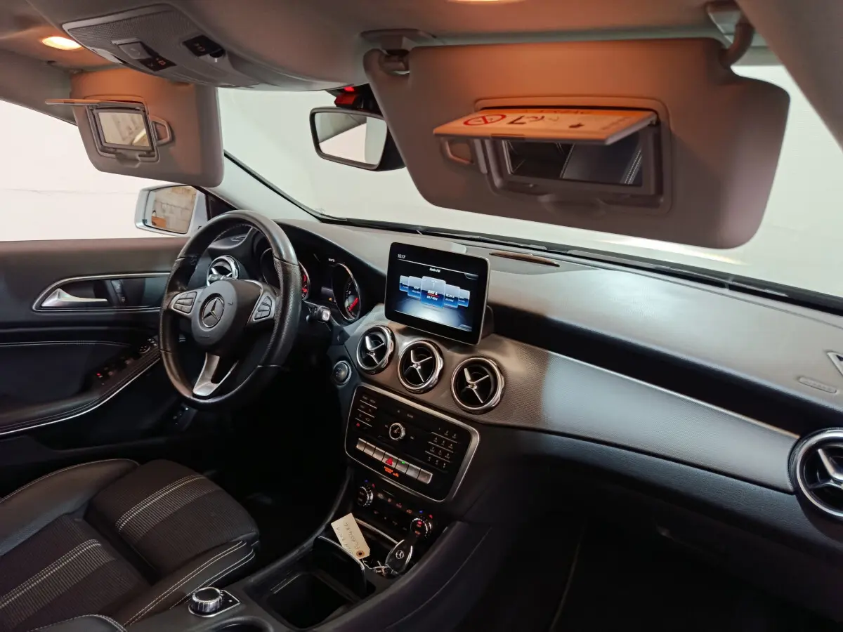Intérieur du Mercedes GLA 200 d Business Executive 2018 vu côté conducteur, tableau de bord noir avec écran central et volant cuir.