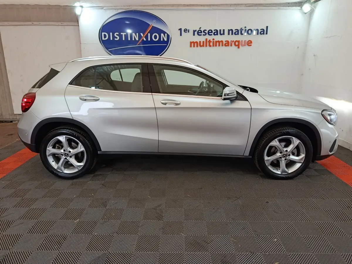 Vue latérale droite d'un Mercedes GLA 200 d gris clair, avec jantes alliage et rétroviseurs électriques dans un showroom.