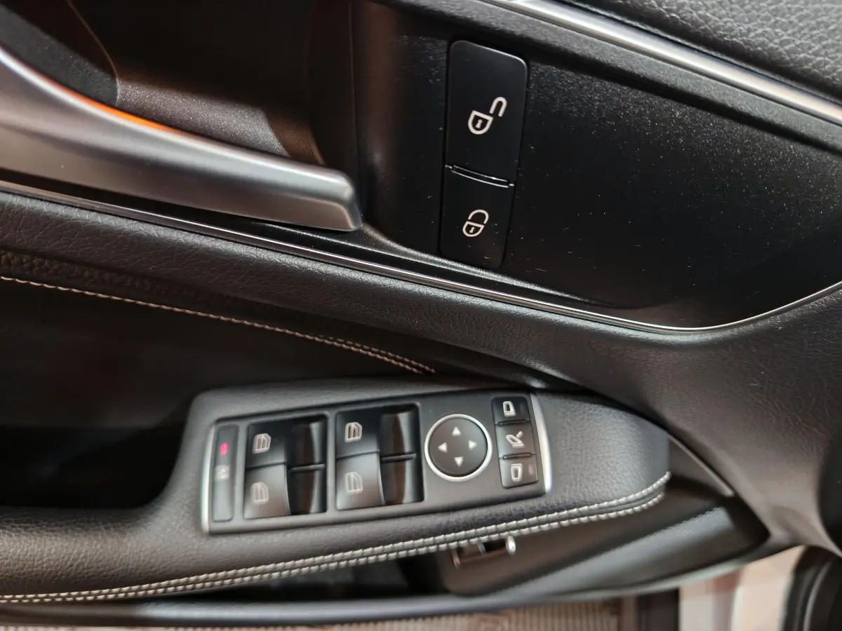 Gros plan sur la porte côté conducteur du Mercedes GLA 200 d gris clair, avec commandes électriques et poignée argentée.
