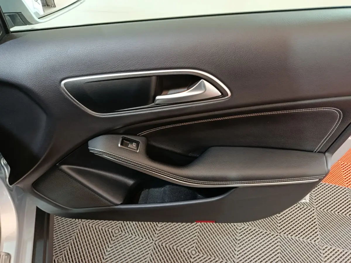 Vue rapprochée de la porte côté gauche d'une Mercedes GLA 200 d gris clair avec garniture noire et surpiqûres blanches.