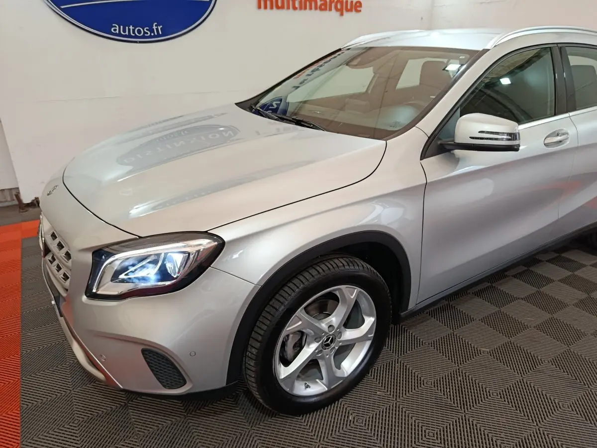 Mercedes GLA 200 d gris clair vu en 3/4 avant droit, avec phares LED allumés et jantes alliage visibles.