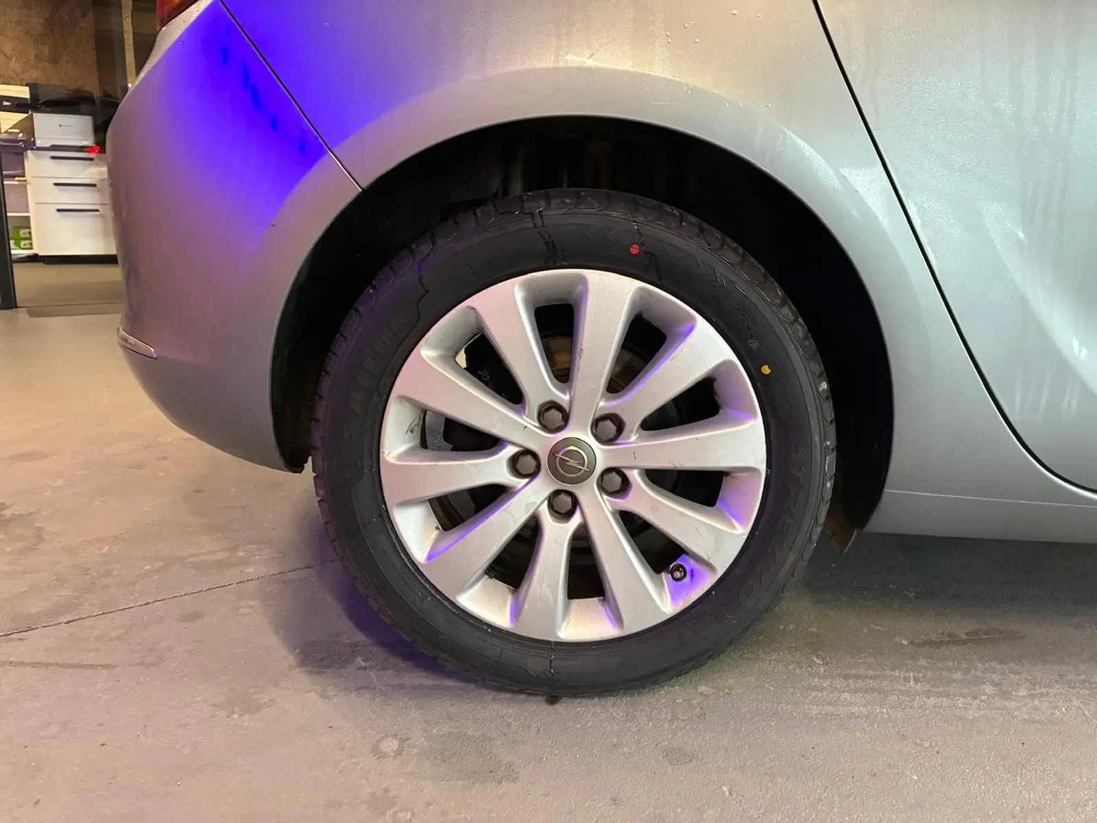 Gros plan sur la roue arrière droite grise d'une Opel Astra 1.6 CDTI 110 diesel de 2015 en intérieur.