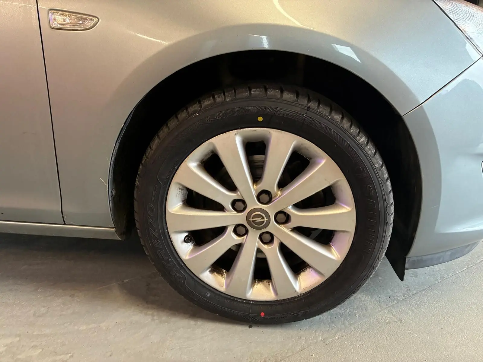 Gros plan sur la roue avant gauche gris métallisé d'une Opel Astra 1.6 CDTI 110 de 2015 avec jante alliage.