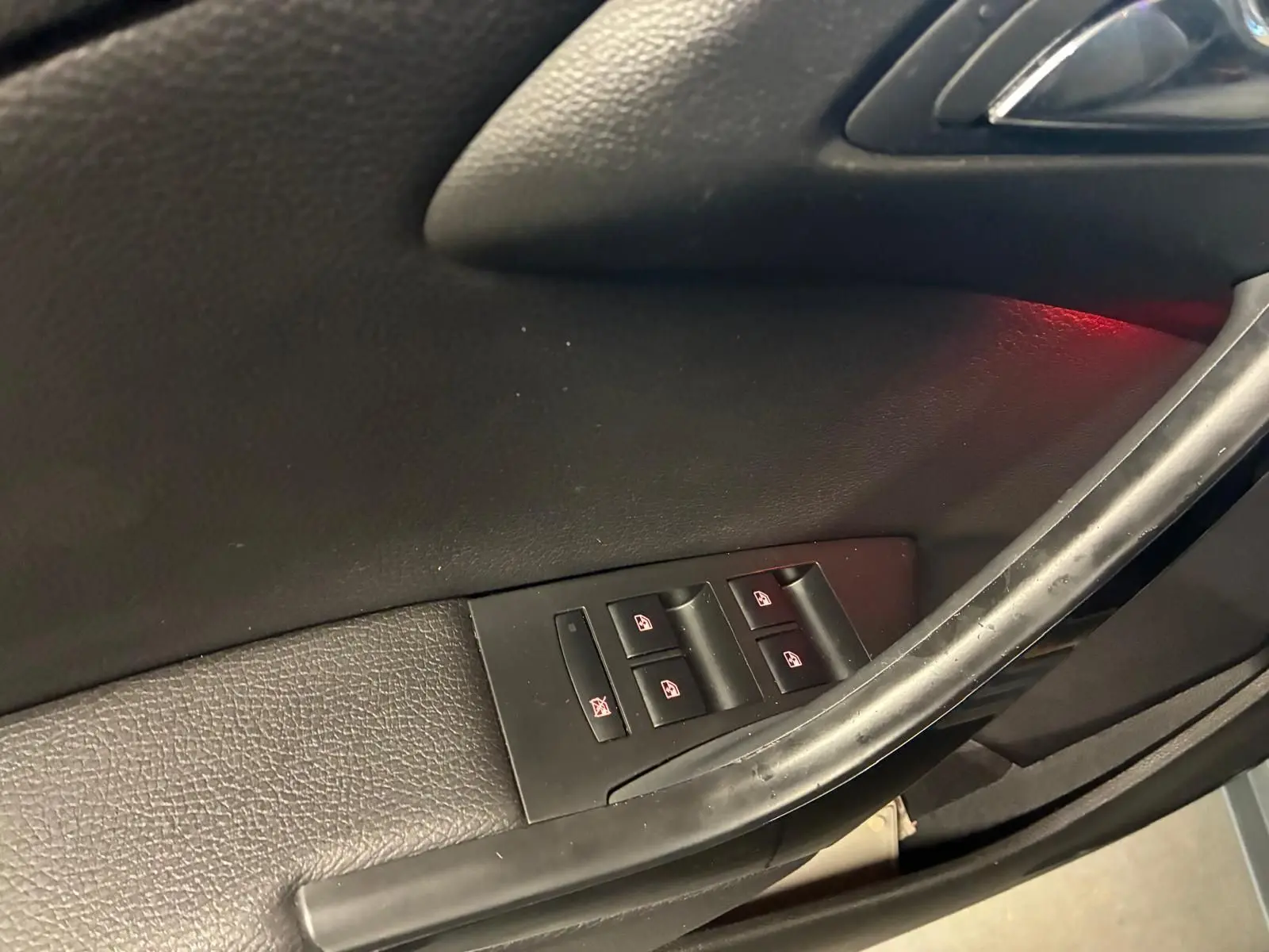 Gros plan sur les commandes des vitres électriques côté gauche de la porte d’une Opel Astra gris 2015.
