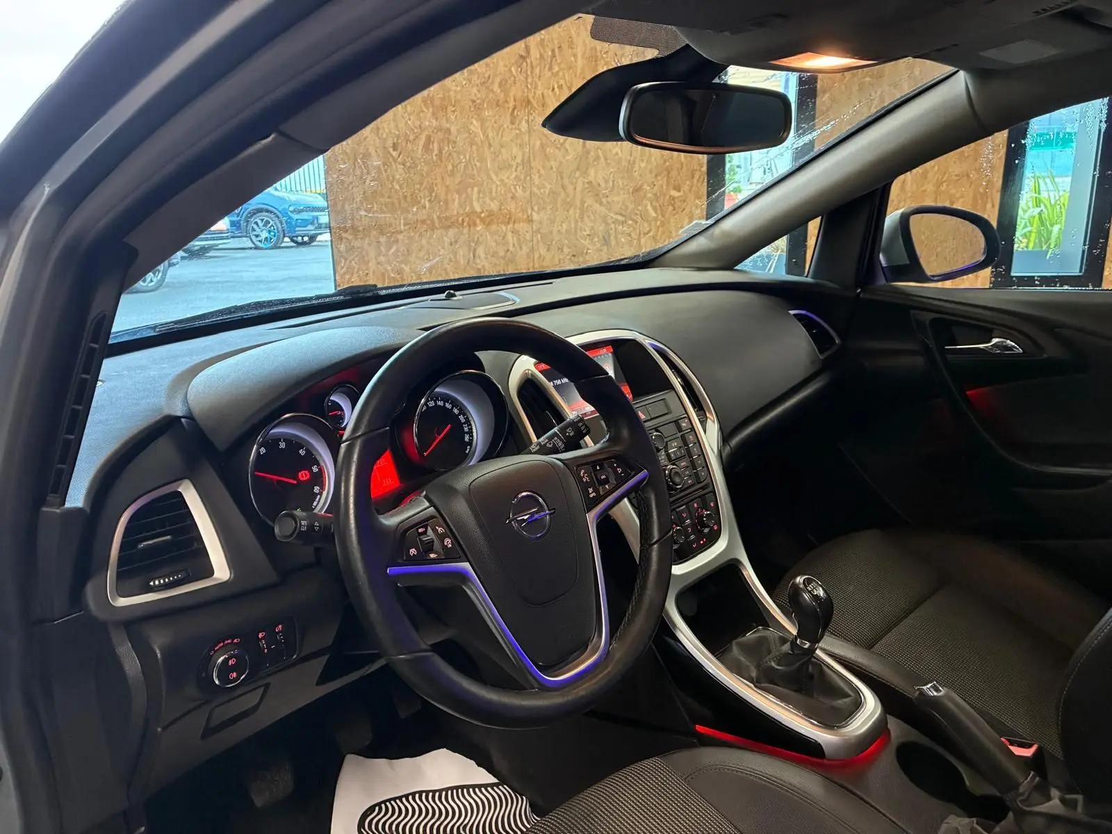 Intérieur de l’Opel Astra 1.6 CDTI 2015, vue côté conducteur, tableau de bord noir avec console centrale et boîte manuelle.