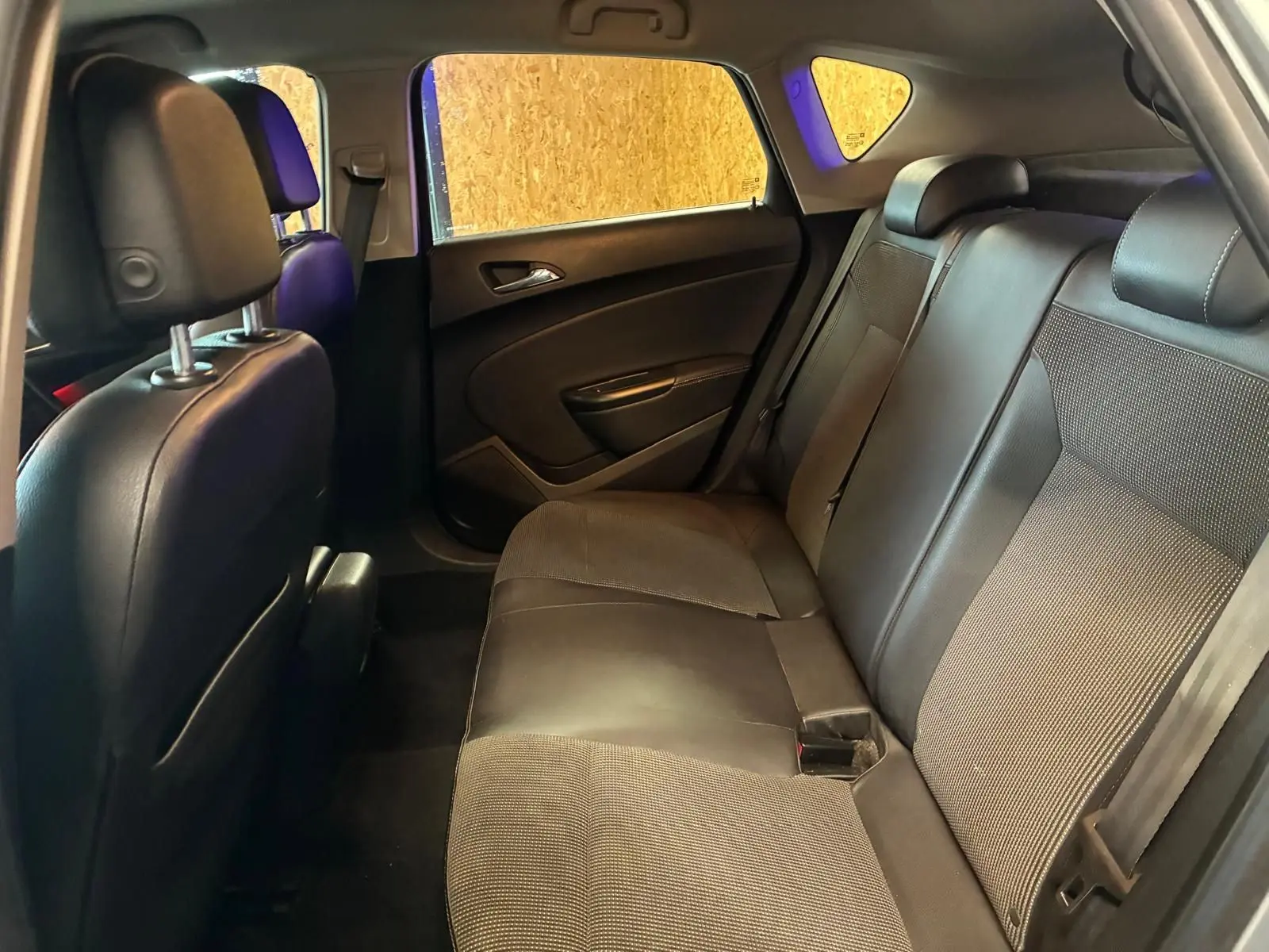 Vue intérieure arrière droite de l’Opel Astra 2015, sièges en tissu et cuir noir, espace passagers visible.