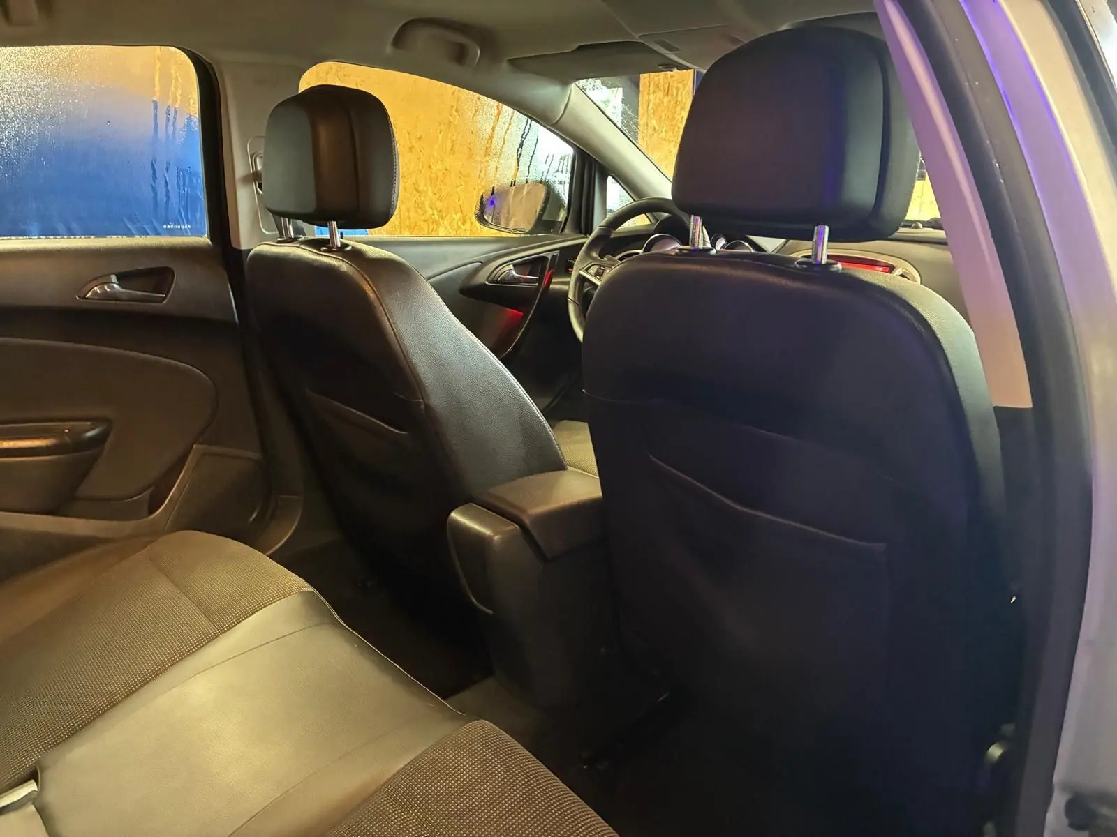 Vue intérieure arrière de l'Opel Astra gris 2015, montrant les sièges avant en cuir noir et la banquette arrière.