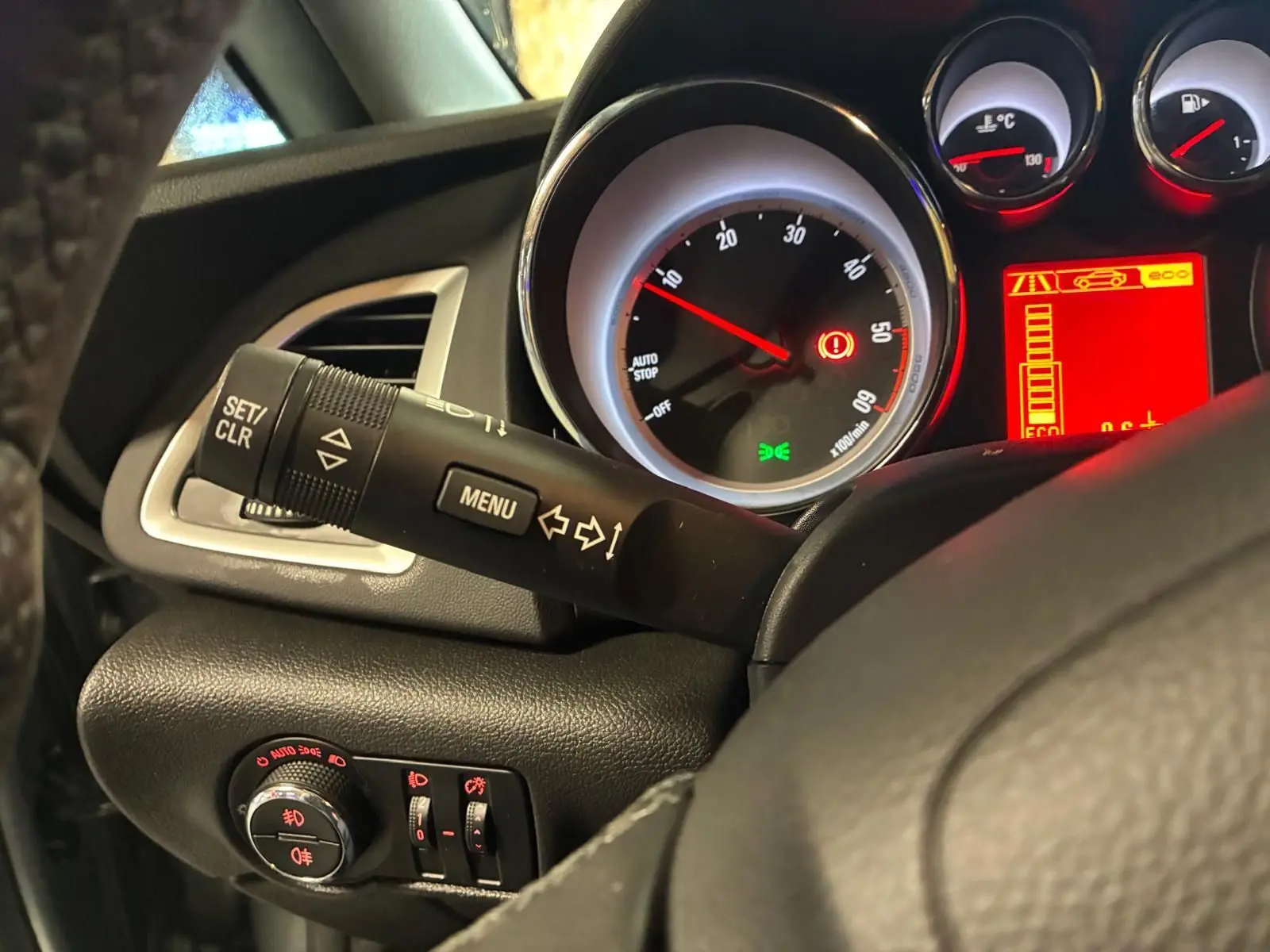 Vue rapprochée du tableau de bord gris d'une Opel Astra 2015, avec compte-tours et commandes au volant visibles.