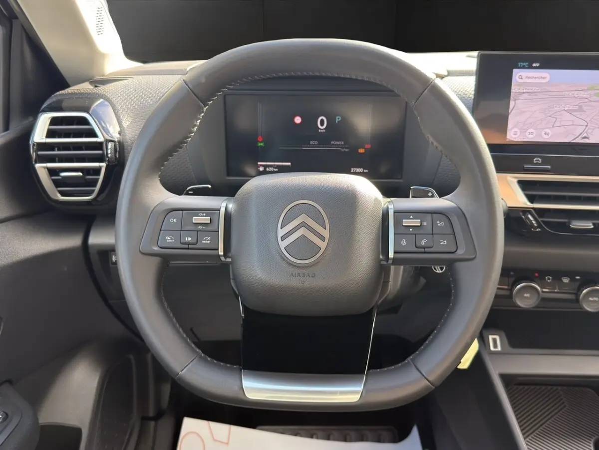 Vue centrée sur le volant cuir multifonctions de la Citroën C4 hybride 2025 avec tableau de bord numérique et écran tactile.