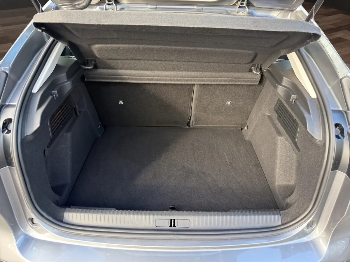 Coffre ouvert vu de l'arrière d'une Citroën C4 hybride gris foncé, espace de chargement propre et spacieux.