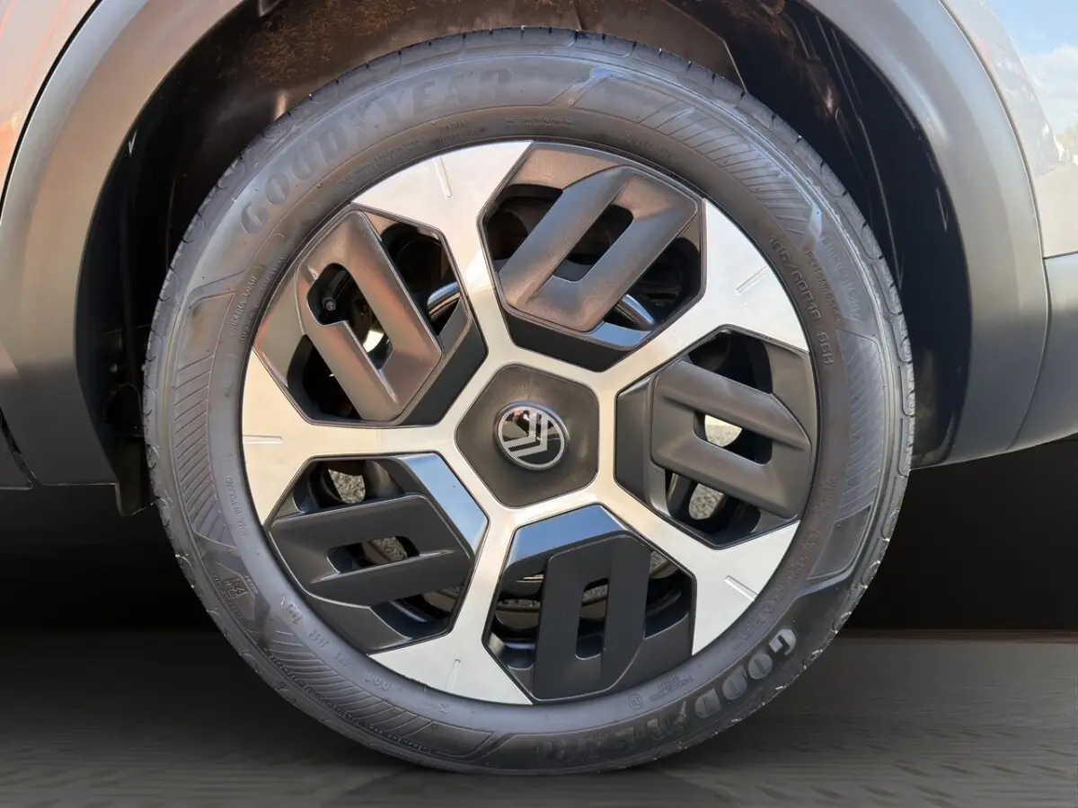 Gros plan sur la roue avant gauche d'une Citroën C4 hybride gris foncé avec jante à design géométrique bicolore.