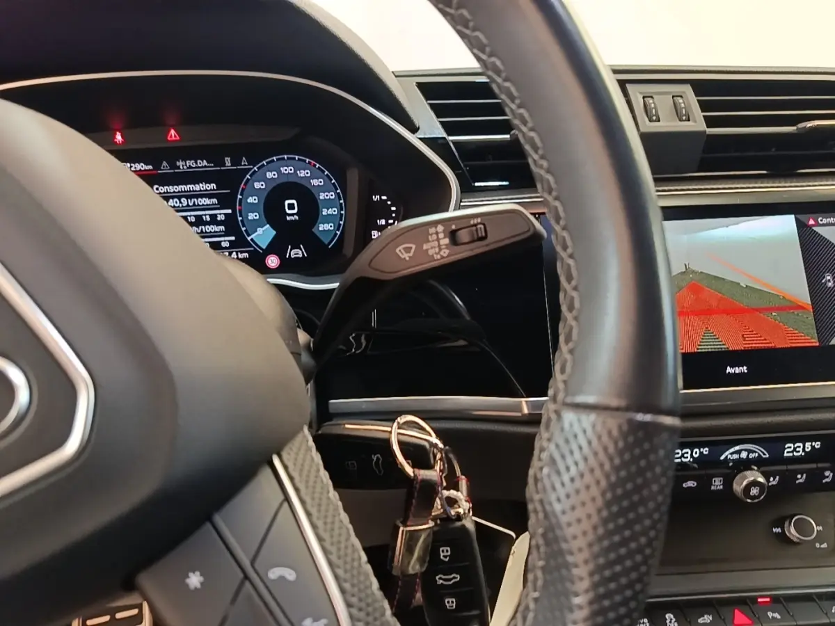 Vue intérieure centrée sur le volant cuir et le tableau de bord digital de l'Audi Q3 Sportback 2024 hybride rechargeable.