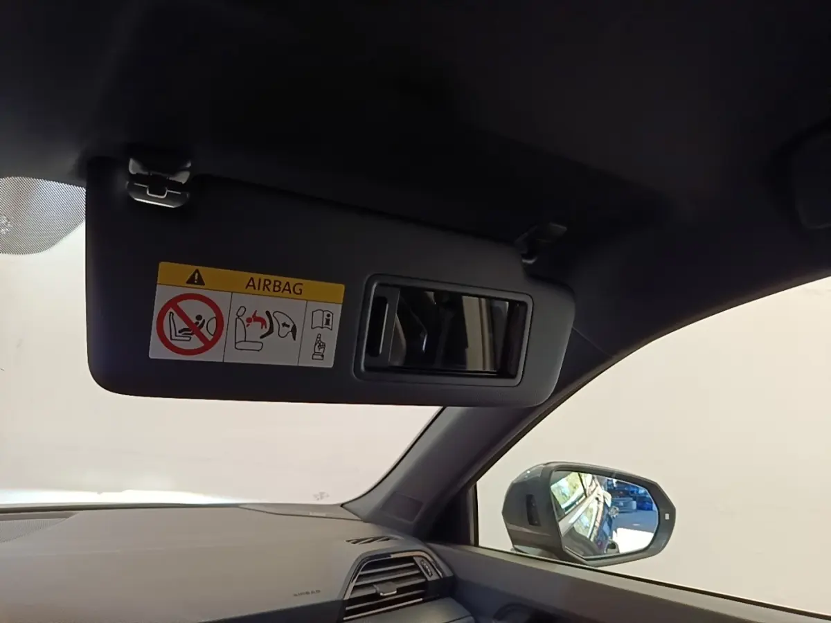Vue intérieure côté conducteur de l'Audi Q3 Sportback gris clair, avec pare-soleil et rétroviseur latéral visible.