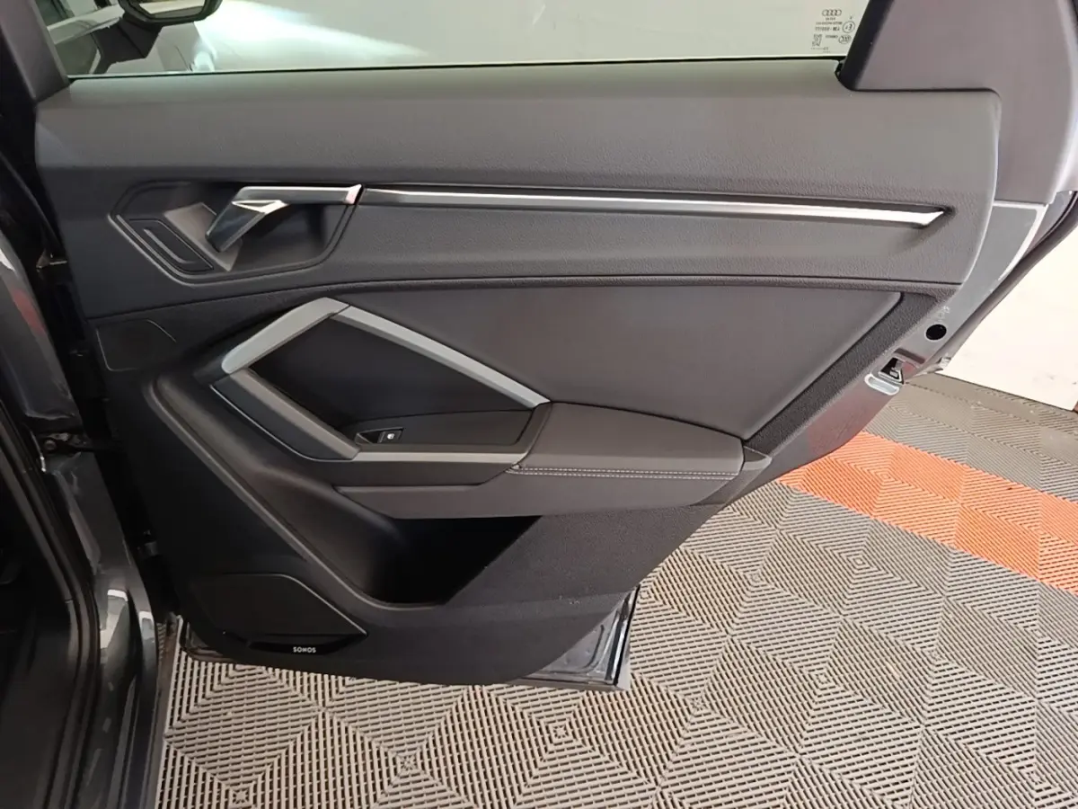 Vue intérieure de la porte arrière droite d’un Audi Q3 Sportback gris clair avec habillage noir et insert argenté.