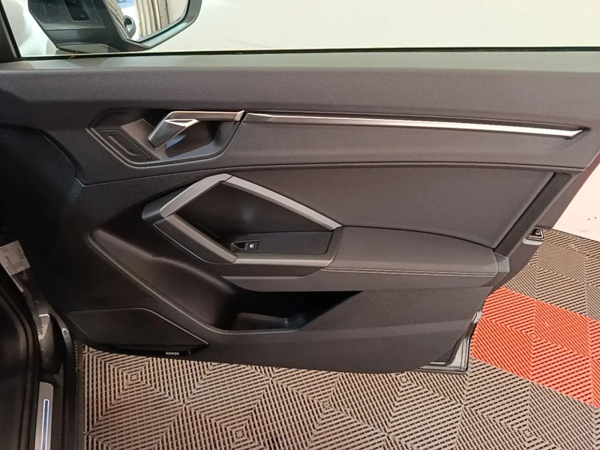 Vue intérieure de la porte avant gauche de l'Audi Q3 Sportback 2024, avec garniture noire et poignée argentée.