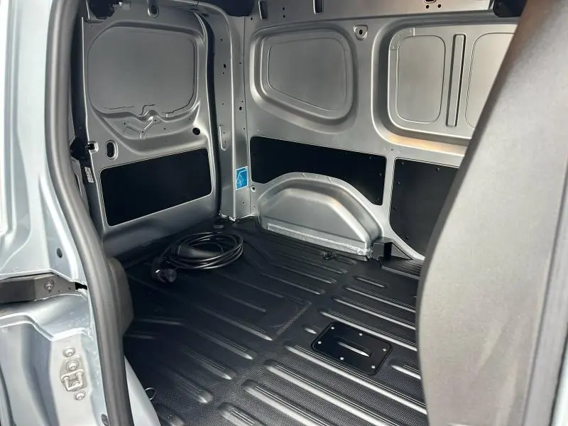 Vue intérieure de la zone de chargement grise du Nissan Townstar L1 EV 2024 avec câble de recharge noir posé au sol.