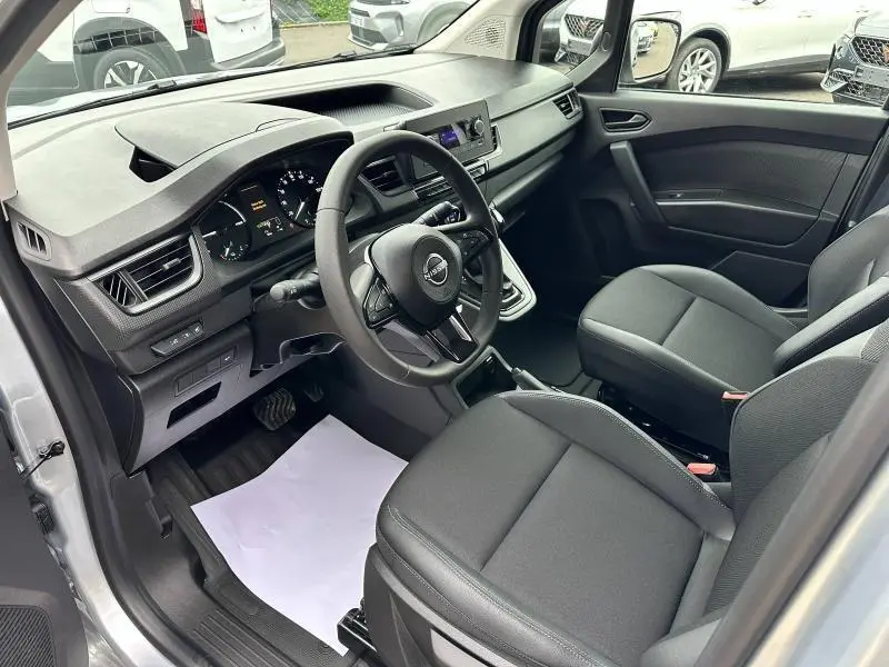 Intérieur avant du Nissan Townstar gris 2024, vue côté conducteur montrant tableau de bord et sièges en tissu noir.