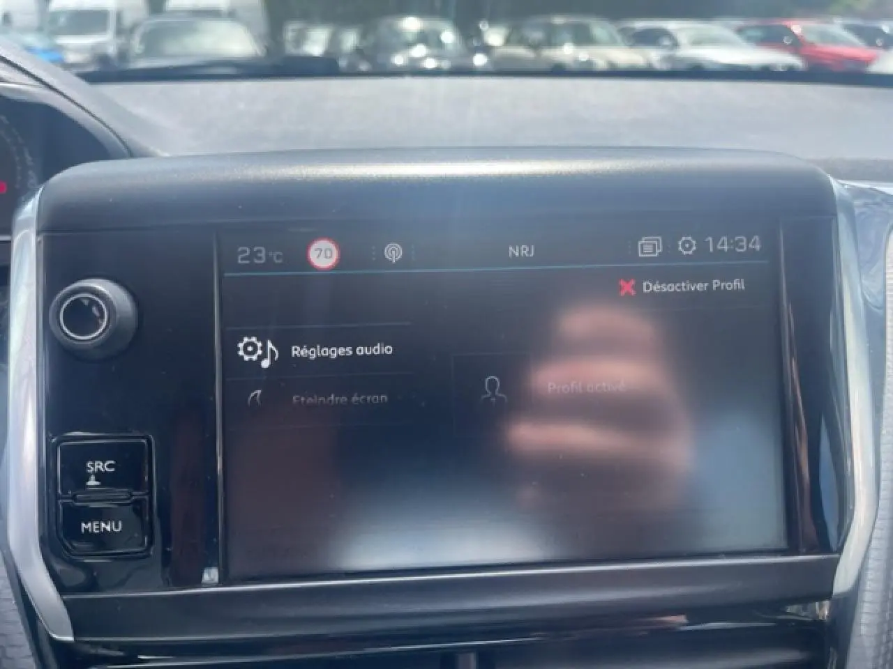 Écran tactile central du tableau de bord de la Peugeot 208 blanc perle, affichant les réglages audio en plein jour.