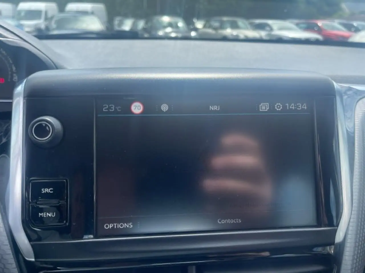 Vue rapprochée de l'écran tactile central noir du tableau de bord d'une Peugeot 208 blanche perle.