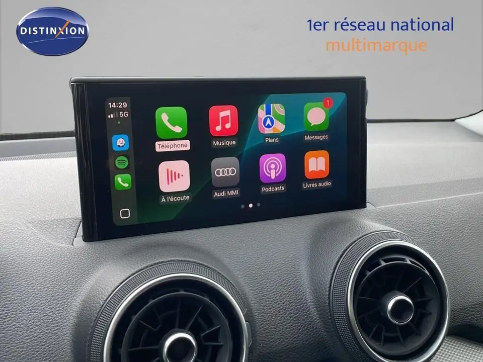 Écran tactile central de l'Audi Q2 2023 affichant les applications Apple CarPlay, avec aérateurs ronds en dessous.
