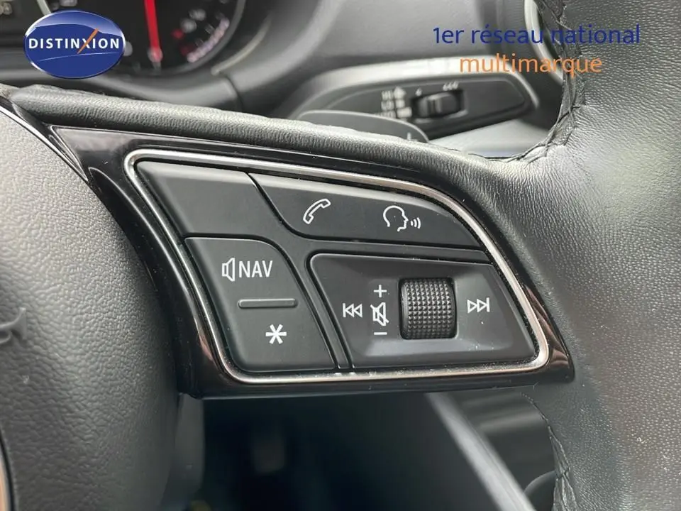 Gros plan sur les commandes audio et navigation au volant cuir noir de l'Audi Q2 35 TFSI S-Line 2023.